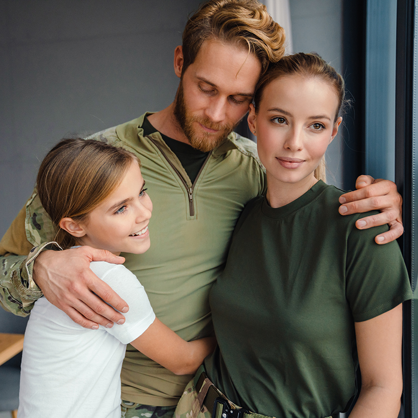 A beautiful, happy family hugging while looking out window at home