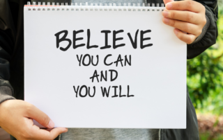Person holding a "Believe you can and you will" sign.